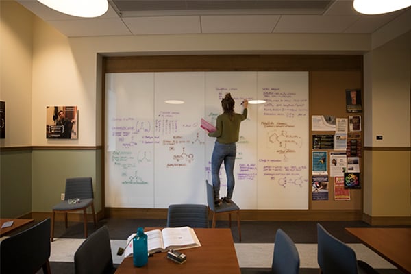 Student studying on whiteboard in Champan Hall