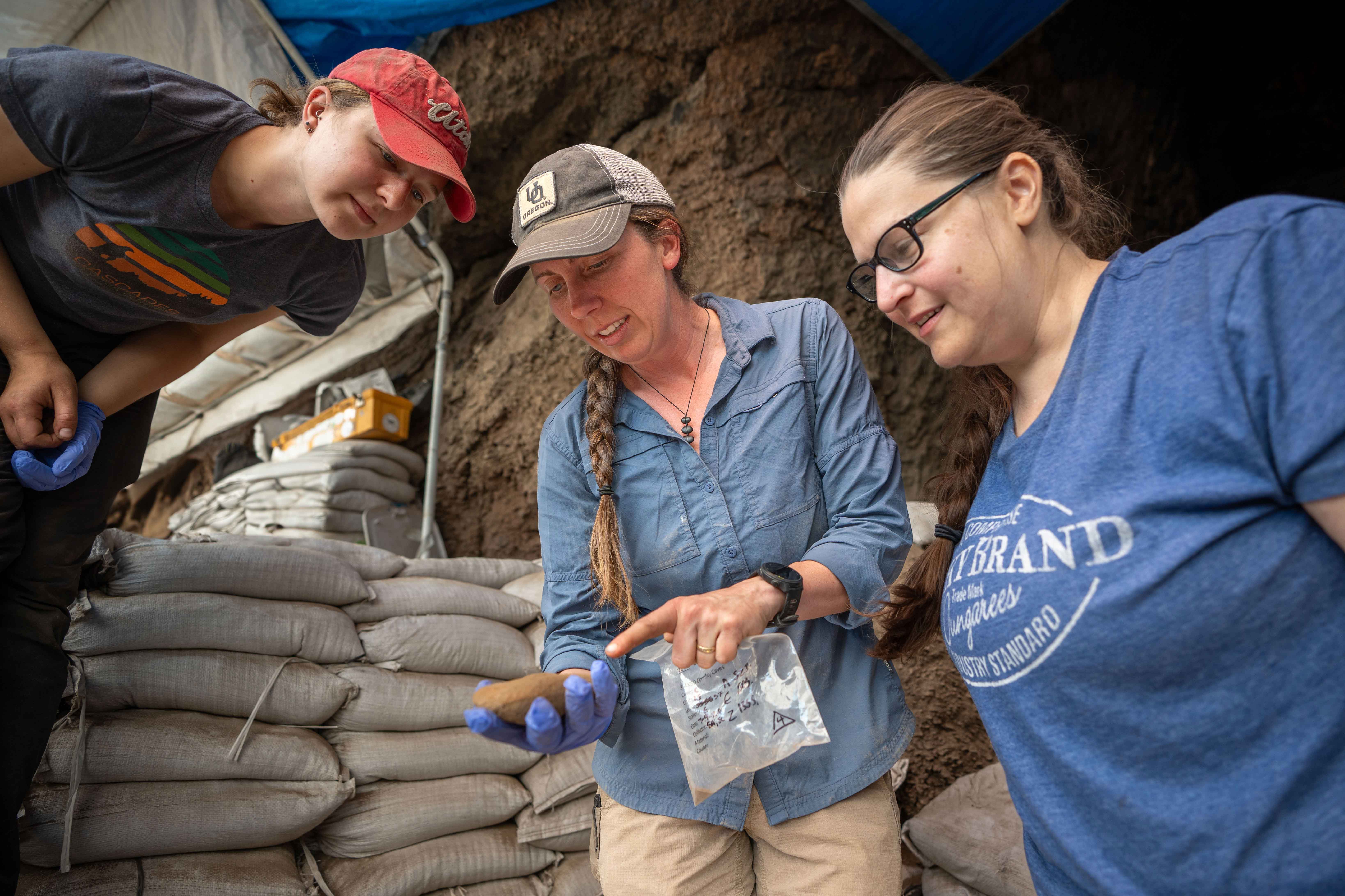 Katelyn McDonough and Stephanie Alexander looking at a stone at the excavation site