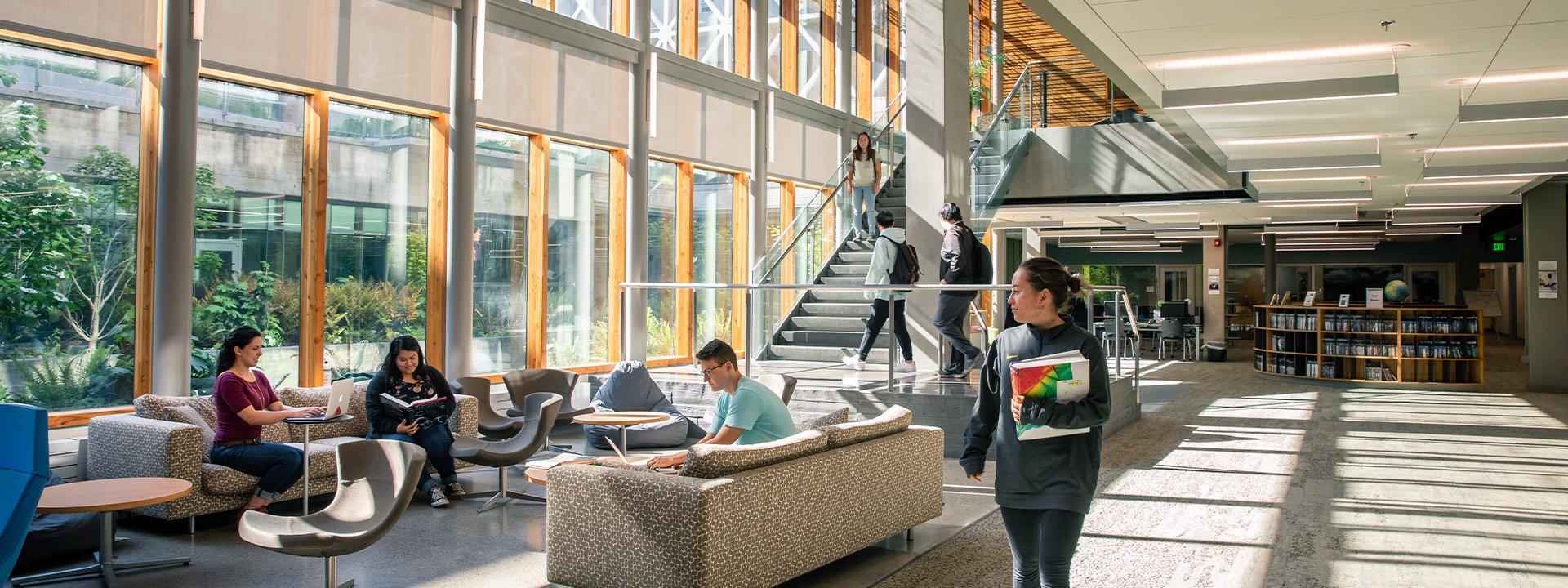 Students doing schoolwork and walking around a UO building lobby