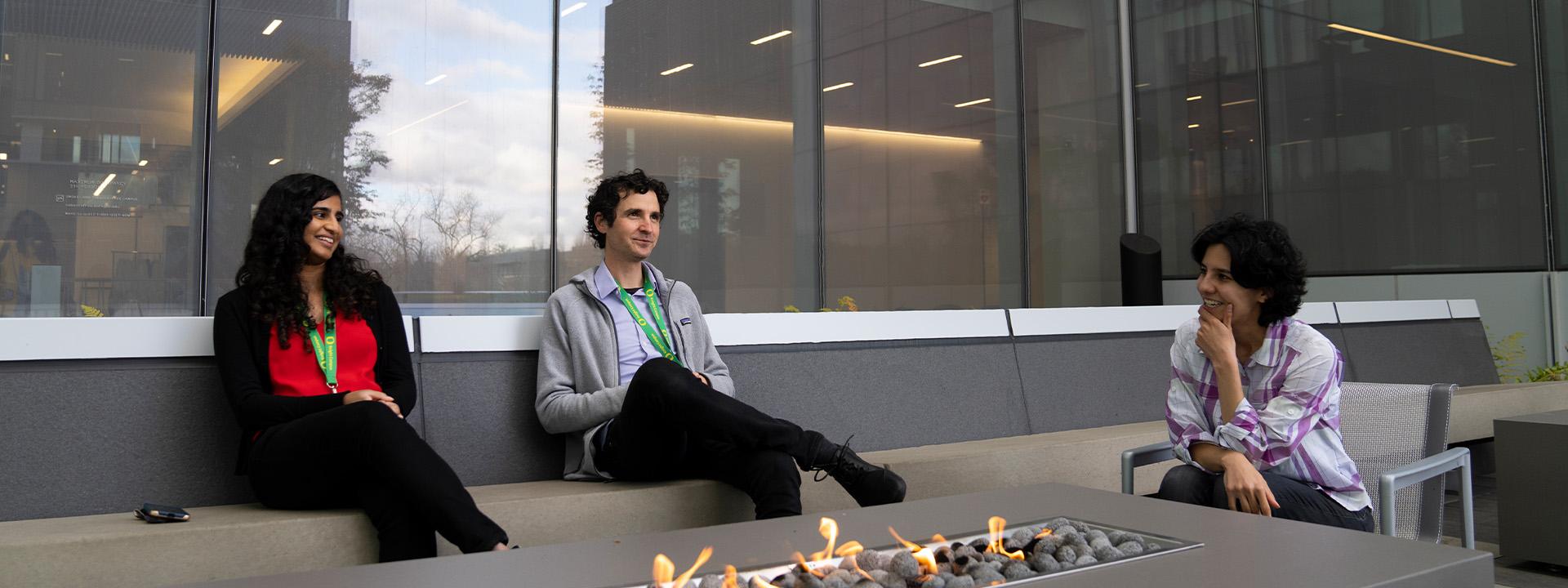 UO students and staff sit around an outdoor fire pit