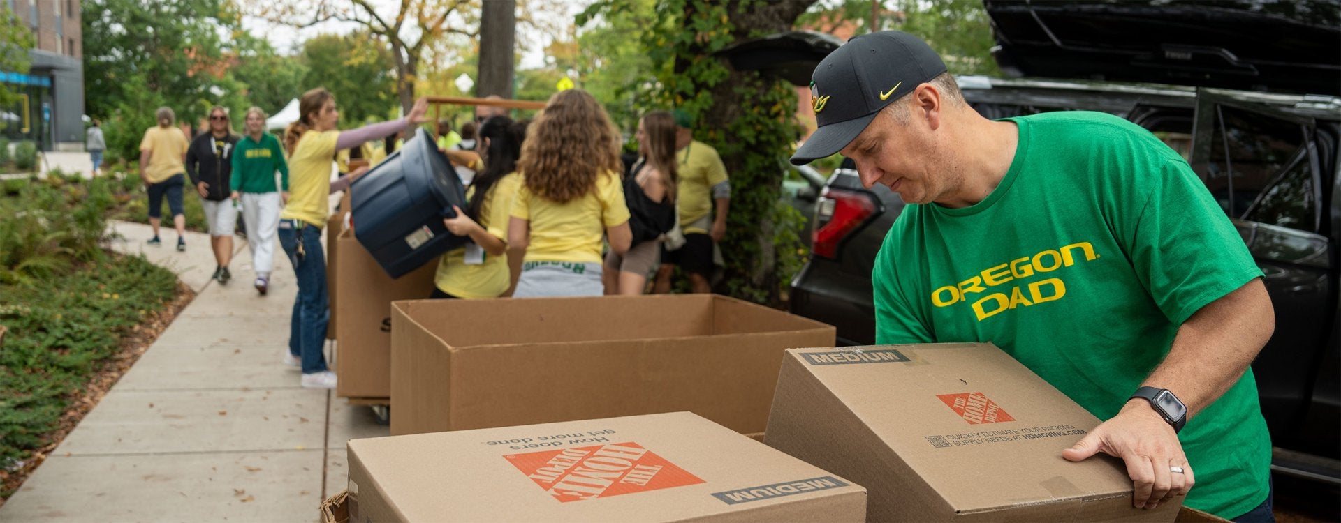 Man in an Oregon Dad shirt helps on Unpack the Quack move-in day