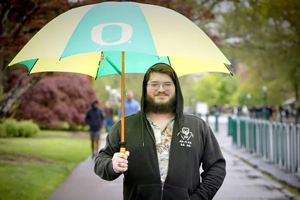 Grad student Alex Rosen stands under an umbrella