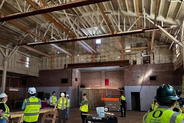 People in hard hats tour inside of Highland Hall