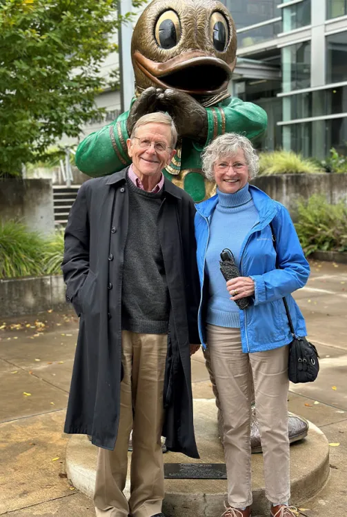 Former UO professor Roger Chickering and Alison Baker (JD ’85) stand in front of a statue of the Oregon Duck