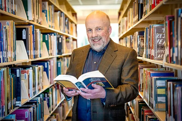Scott Drumm holding open book in library