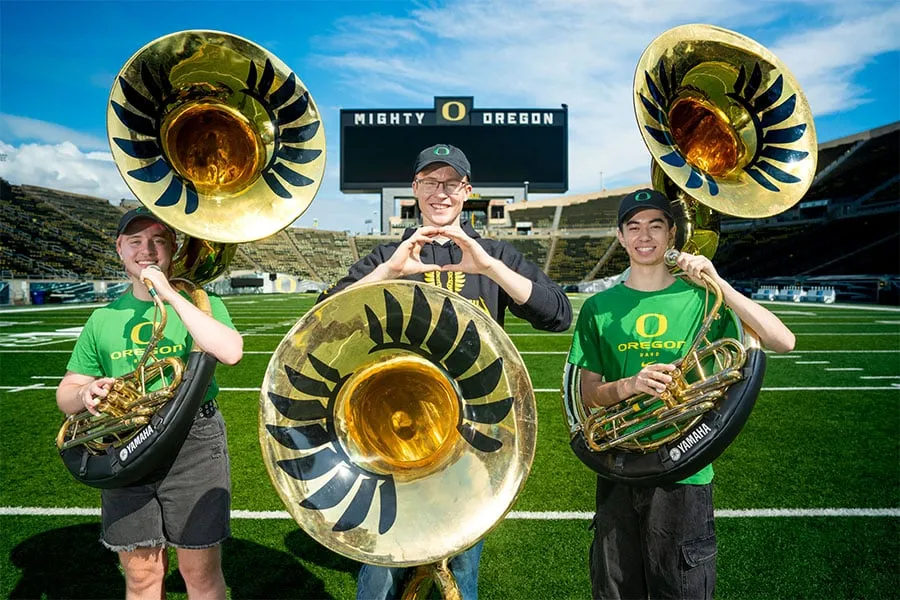 3 figures holding sousaphones in Autzen stadium