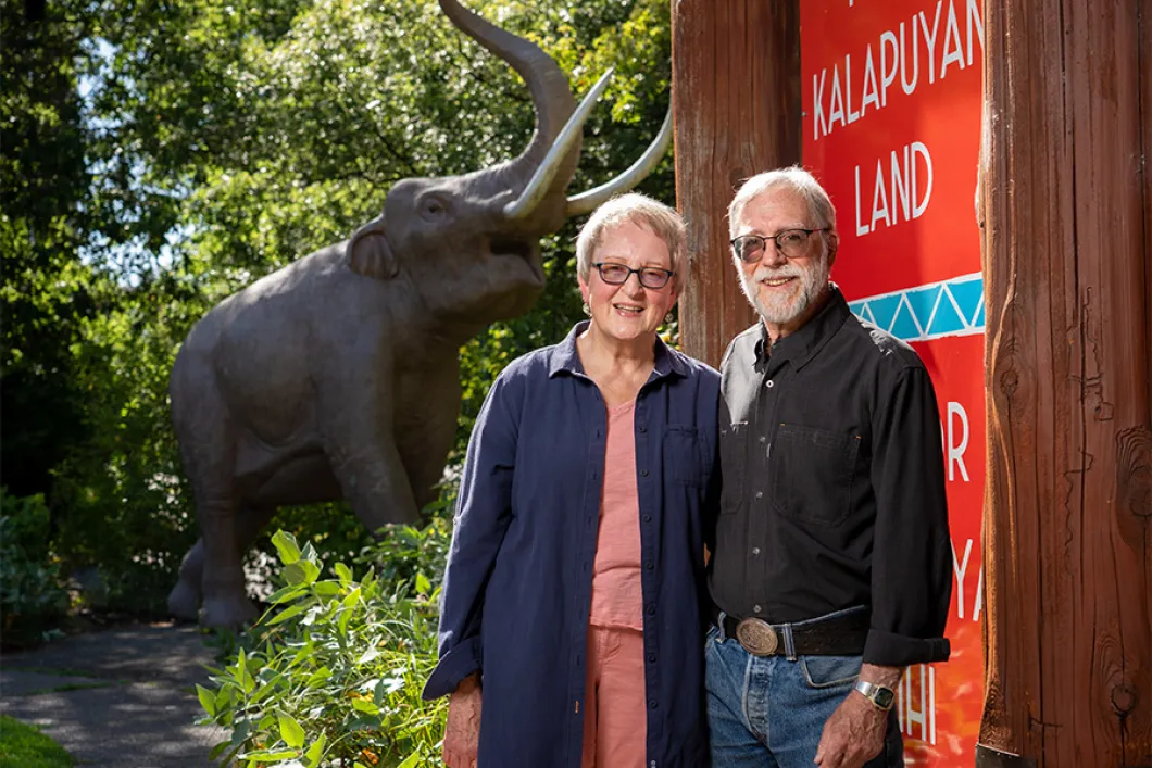 Elderly couple standing next to elephant statue