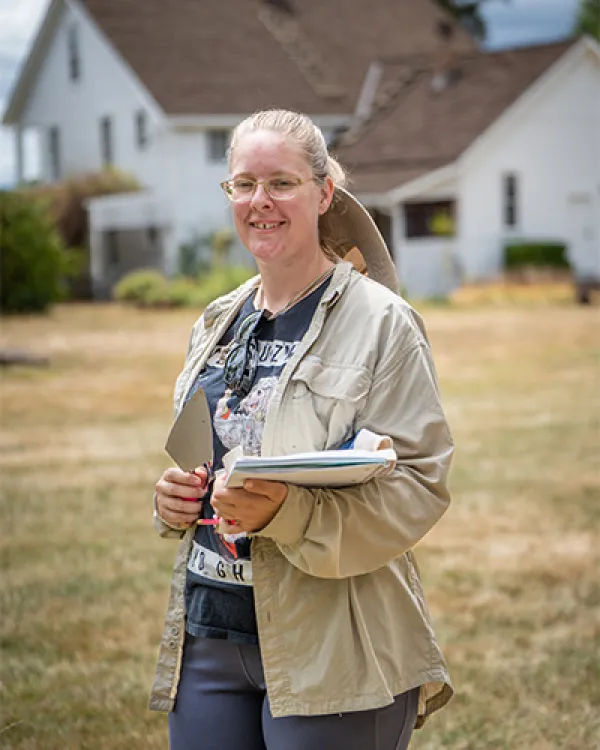 Blonde white woman standing outside in a tan jacket