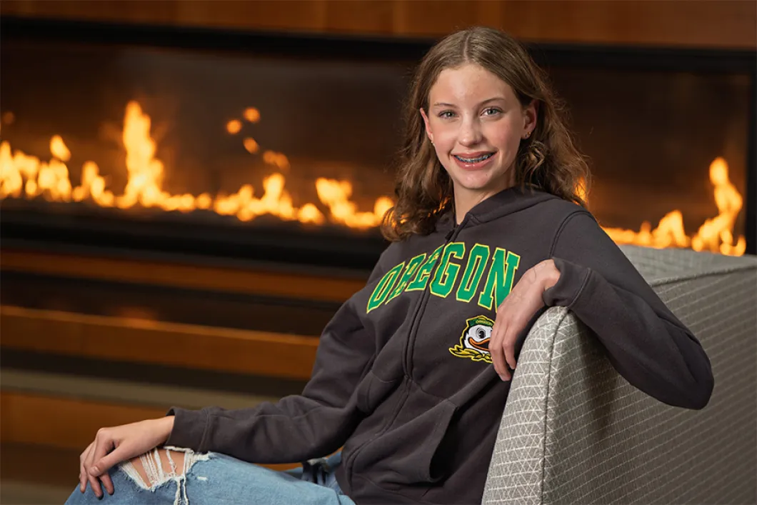 Girl in Oregon gear sititng in front of a hearth