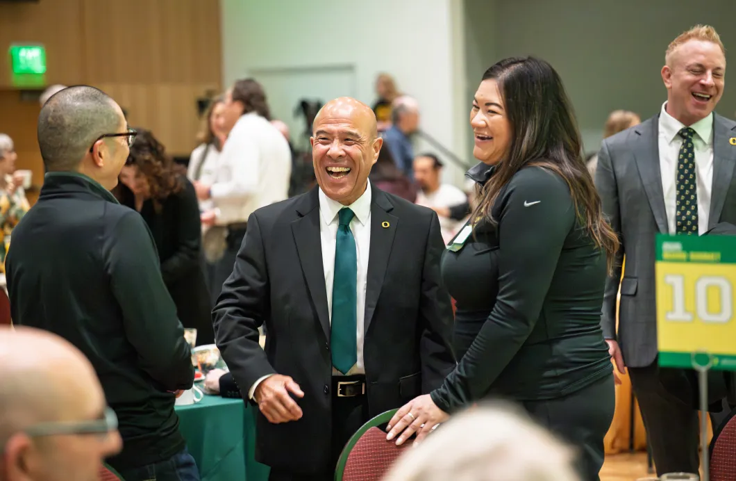 Three people laugh together at a board summit reception. 