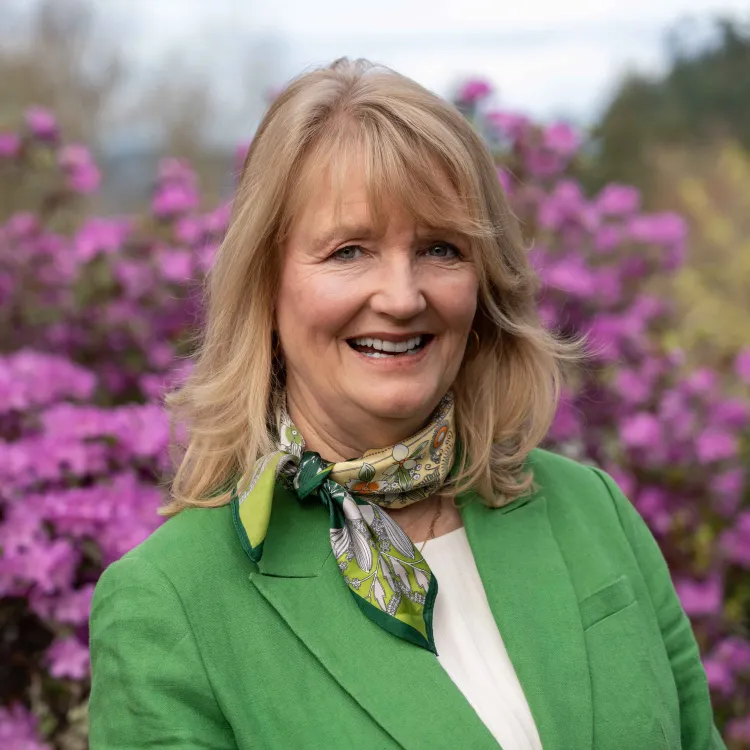 A smiling woman with blond hair and a green blazer