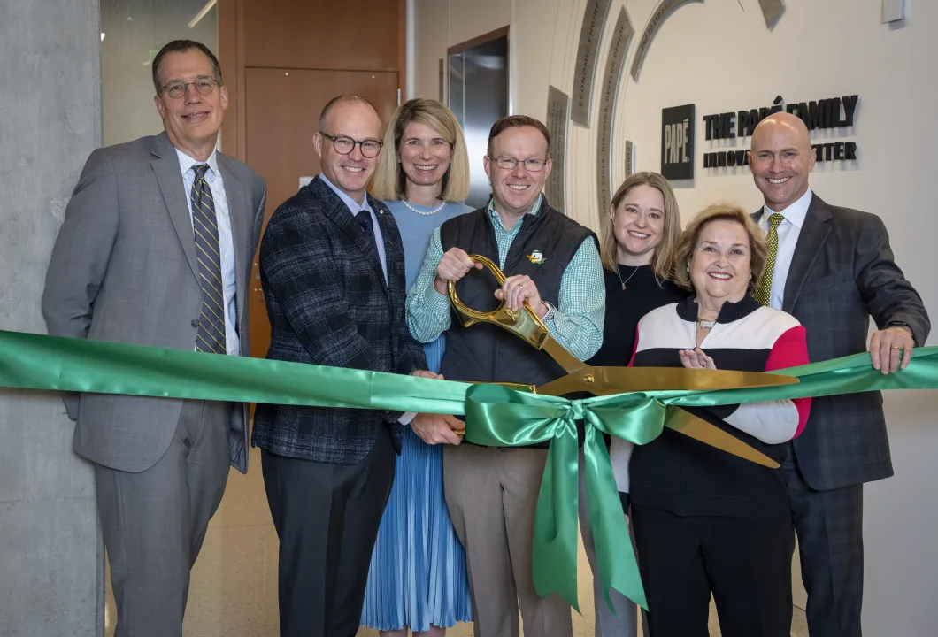 The Papé family and President Scholz stand with oversized scissors, poised to cut a green ribbon. 