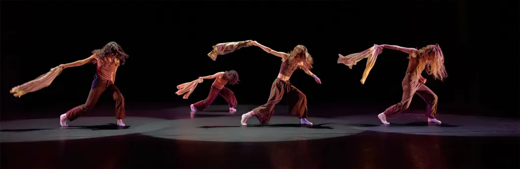 Four dancers perform on stage with a dark background