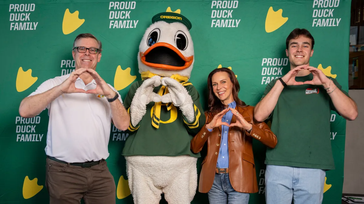 Aaron, Brooke Shelby, and their son, Pierce, pose with the Oregon Duck mascot while creating an Oregon logo
