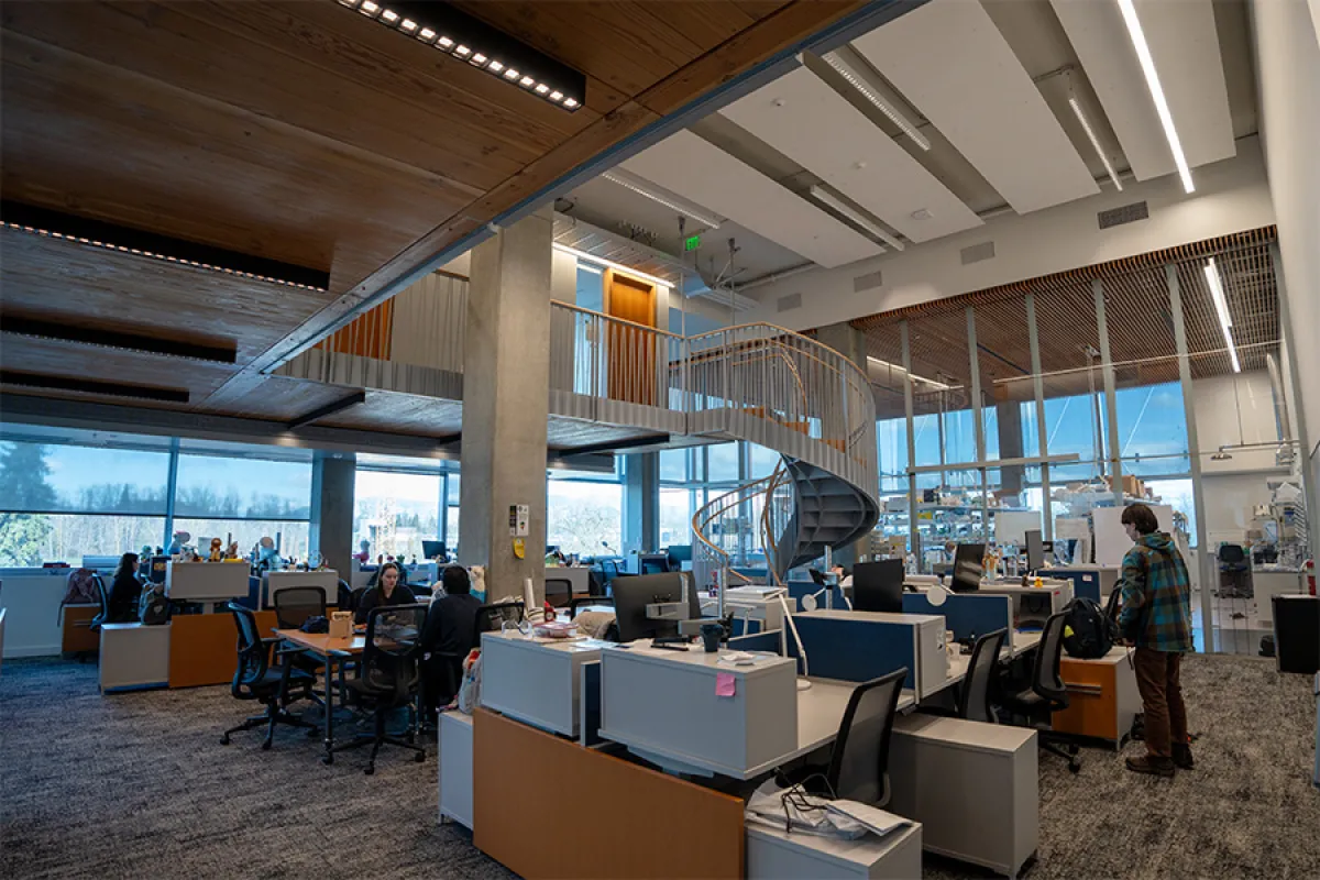 The interior of a building on Knight Campus, containing desks and chairs, as well as a spiral staircase leading to an upstairs space.