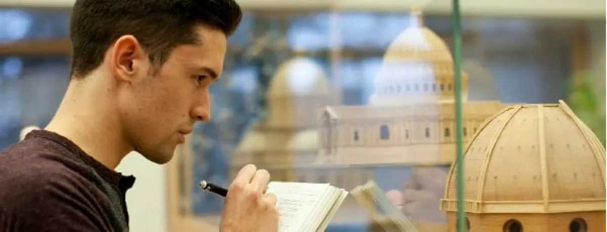 UO Student taking notes while reviewing diagram of building