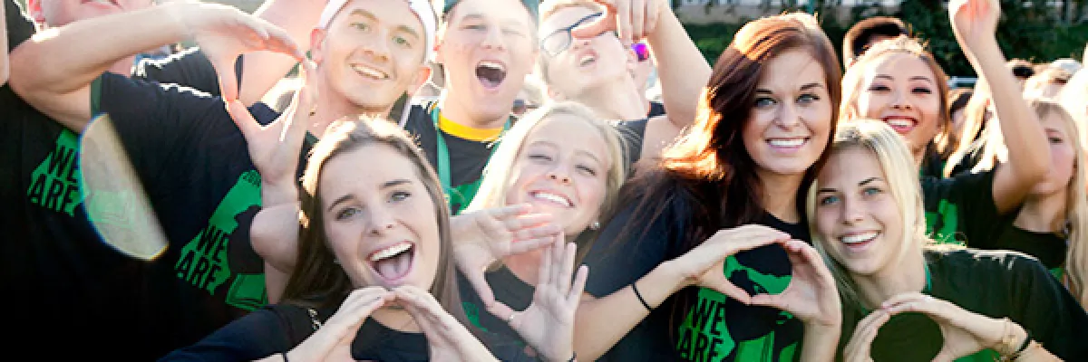 UO students wearing "We Are Oregon" black t-shirts and throwing the O hand gesture