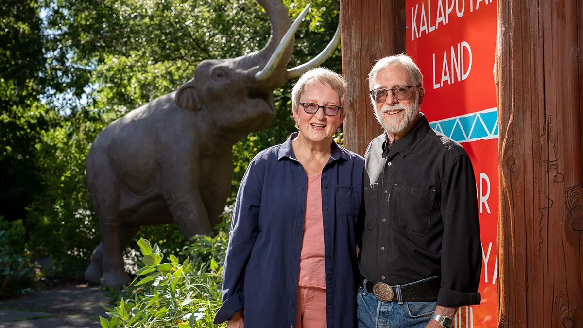 Elderly couple standing next to elephant statue