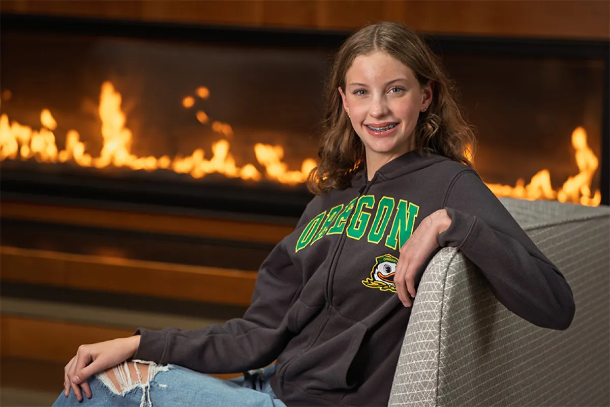 Girl in Oregon gear sititng in front of a hearth