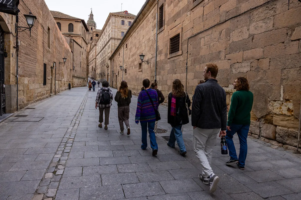 Students walking in a European alleyway between old stone walls