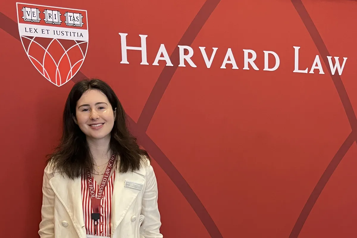 Beatrice Kahn standing in front of a red wall with the words Harvard Law 