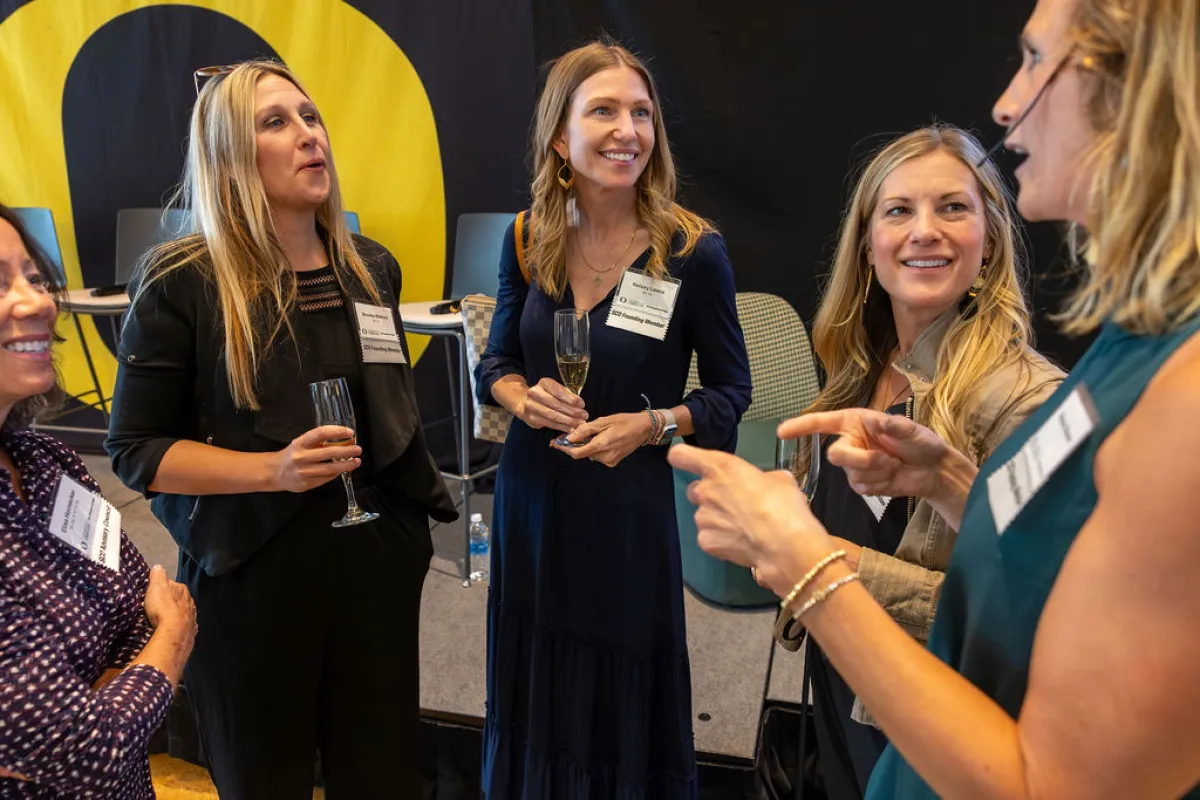 A group of women stand in a circle chatting. 