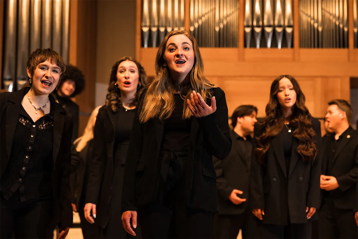 Group of students singing on the stage for a choir concert at Beall hall