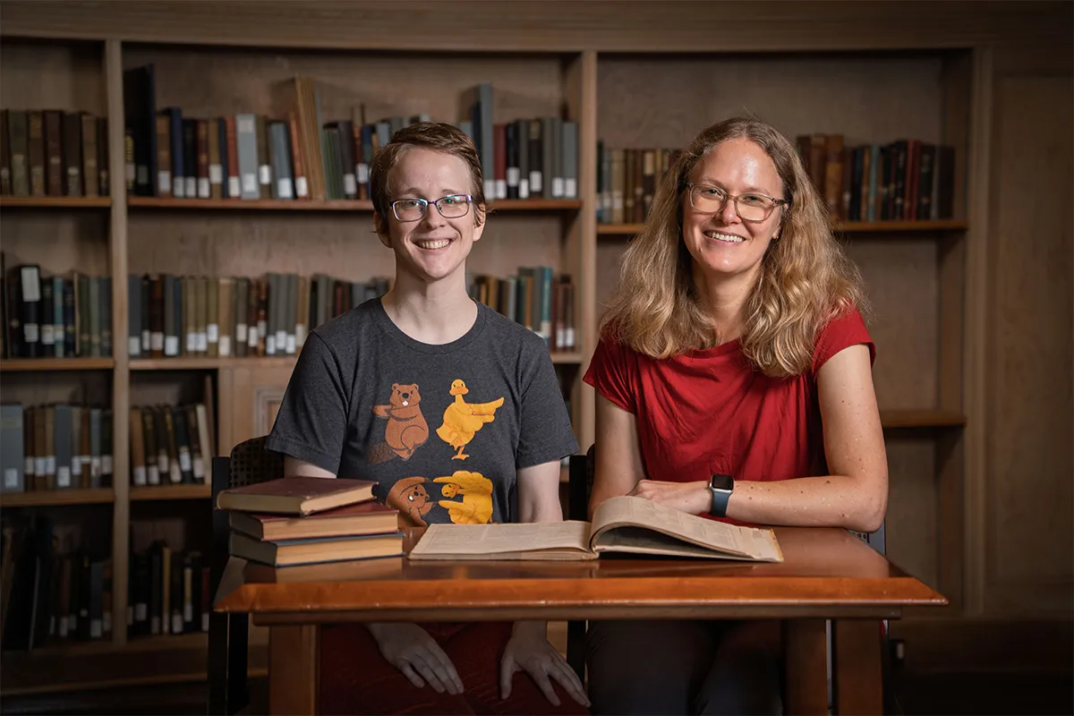 Kit Hungerford and Annelise Heinz sitting in the library looking at books
